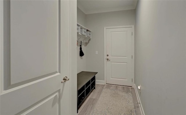 mudroom with baseboards, ornamental molding, and light wood-style floors