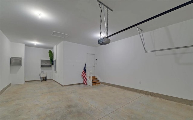 garage with a garage door opener, an AC wall unit, and baseboards