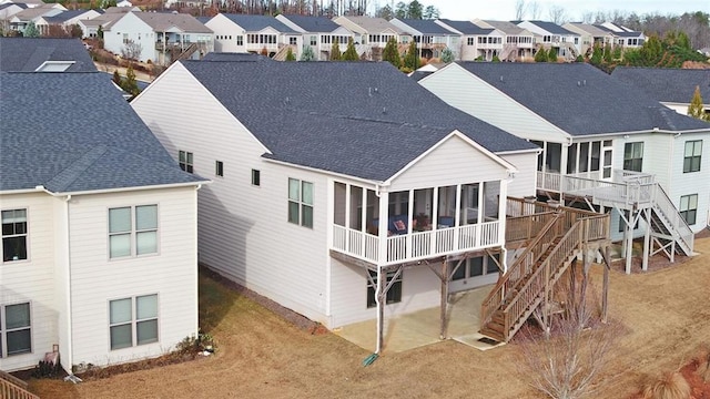 back of property with a sunroom, stairs, a residential view, and a shingled roof