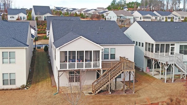 back of house featuring a sunroom, stairs, a residential view, and roof with shingles