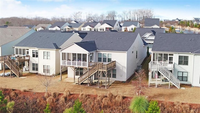 rear view of property with a sunroom, a residential view, stairway, roof with shingles, and a wooden deck