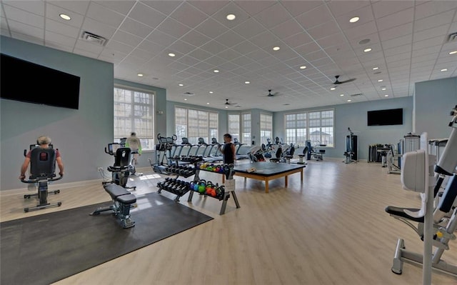 workout area featuring a ceiling fan, visible vents, baseboards, and wood finished floors