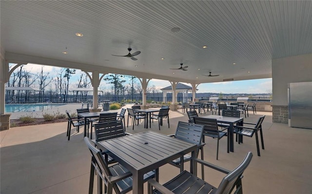 view of patio / terrace featuring a community pool, a ceiling fan, and outdoor dining space