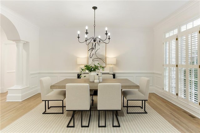 3795 Newport Bay Dr, Alpharetta, GA 30005 - dining room featuring light wood-style floors, a chandelier, arched walkways, decorative columns, and wainscoting