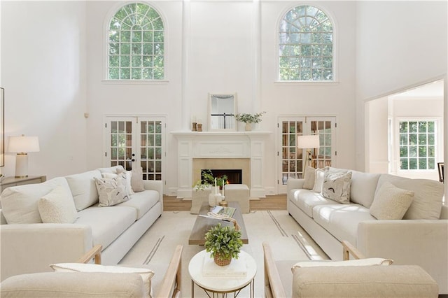 3795 Newport Bay Dr, Alpharetta, GA 30005 - living area with french doors, a towering ceiling, healthy amount of natural light, a warm lit fireplace, and light wood finished floors