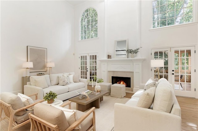 3795 Newport Bay Dr, Alpharetta, GA 30005 - living room with french doors, a towering ceiling, light wood-style flooring, and a lit fireplace