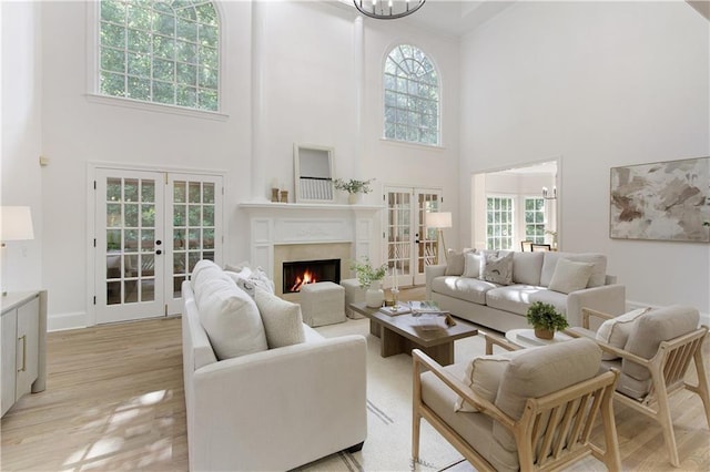 3795 Newport Bay Dr, Alpharetta, GA 30005 - living area with french doors, a high ceiling, a warm lit fireplace, light wood-style floors, and plenty of natural light