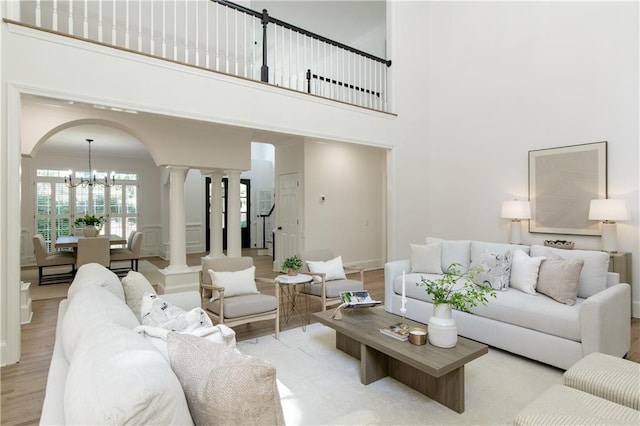 3795 Newport Bay Dr, Alpharetta, GA 30005 - living room featuring a chandelier, wood finished floors, a towering ceiling, ornate columns, and arched walkways
