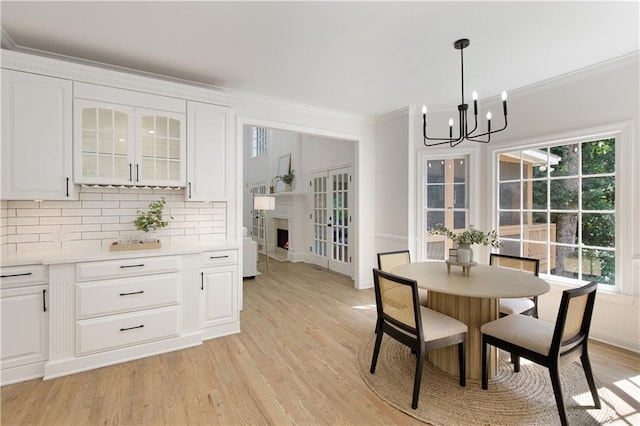 3795 Newport Bay Dr, Alpharetta, GA 30005 - dining area featuring ornamental molding, a chandelier, light wood-type flooring, and a lit fireplace