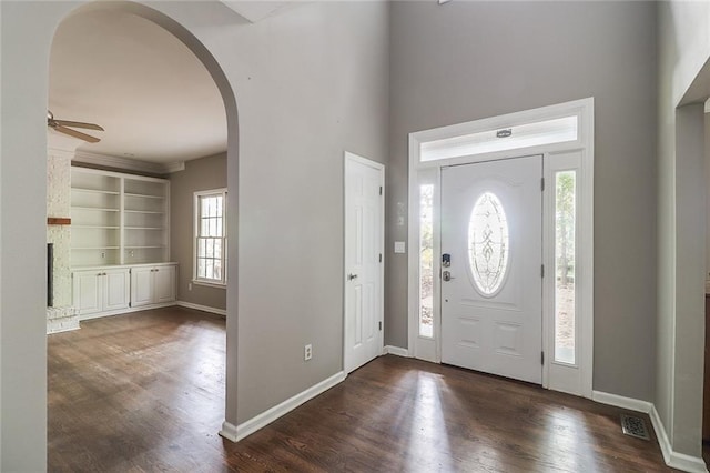 foyer entrance featuring a brick fireplace, dark hardwood / wood-style flooring, plenty of natural light, and ceiling fan