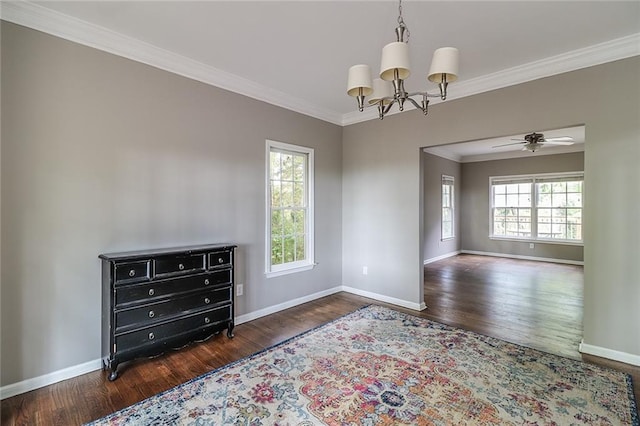 empty room with ceiling fan with notable chandelier, a wealth of natural light, dark hardwood / wood-style flooring, and crown molding