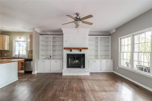 unfurnished living room featuring a brick fireplace, dark hardwood / wood-style flooring, plenty of natural light, and sink