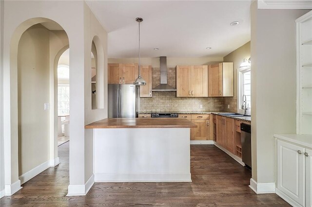 kitchen with decorative light fixtures, wall chimney range hood, butcher block countertops, sink, and stainless steel appliances