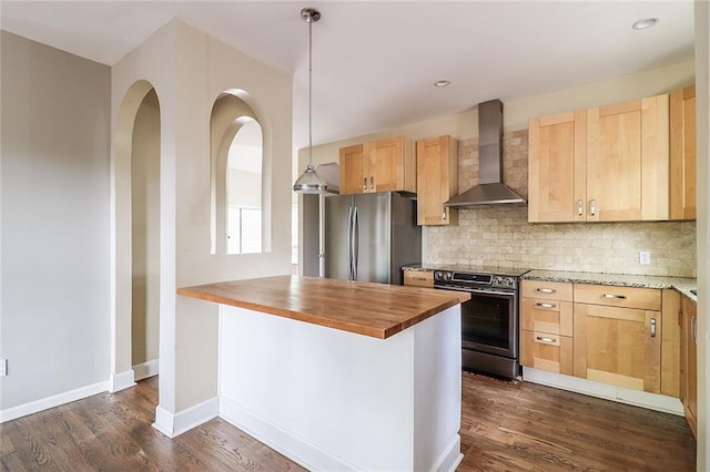 kitchen with butcher block counters, stainless steel appliances, backsplash, hanging light fixtures, and wall chimney exhaust hood