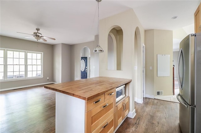 kitchen featuring ceiling fan, stainless steel refrigerator, hanging light fixtures, dark hardwood / wood-style flooring, and wood counters