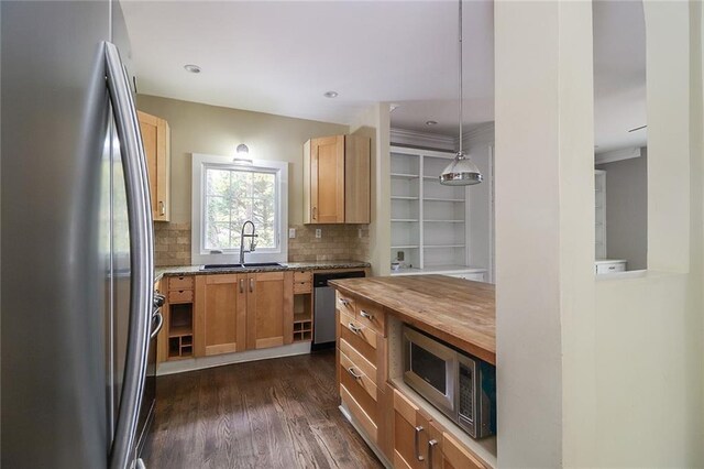 kitchen featuring appliances with stainless steel finishes, backsplash, dark wood-type flooring, hanging light fixtures, and sink