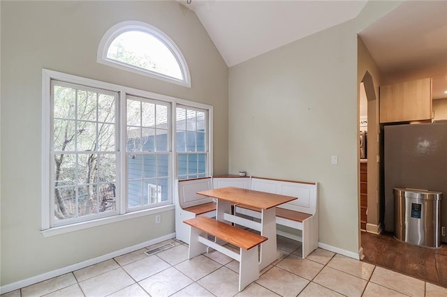 tiled dining space featuring vaulted ceiling