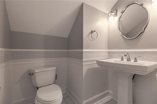 bathroom featuring lofted ceiling, tile patterned flooring, and toilet