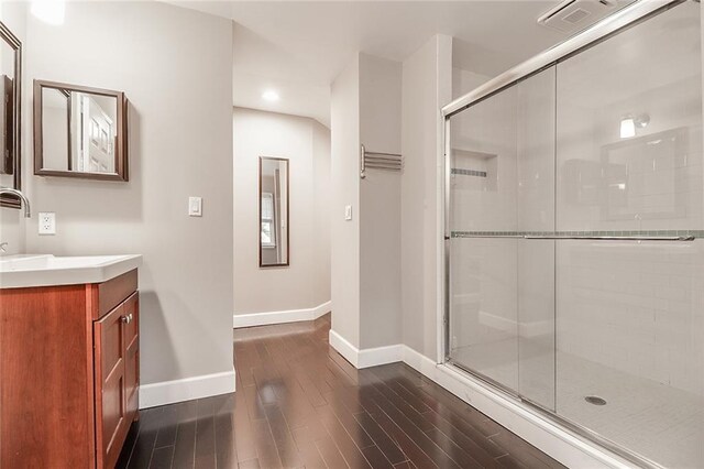 bathroom with a shower with shower door, vanity, and hardwood / wood-style floors