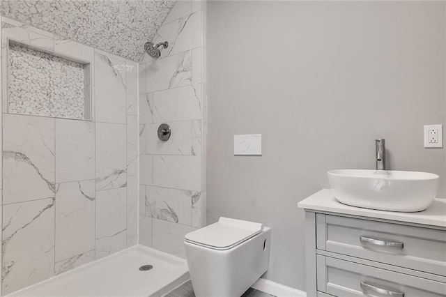 bathroom featuring toilet, lofted ceiling, tiled shower, and vanity