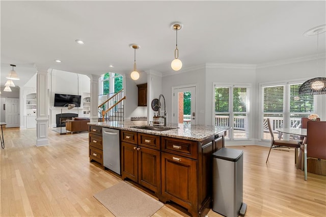 kitchen with light hardwood / wood-style flooring, ornate columns, a center island with sink, and decorative light fixtures