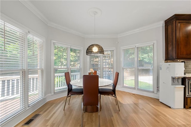 dining area with crown molding and light wood-type flooring