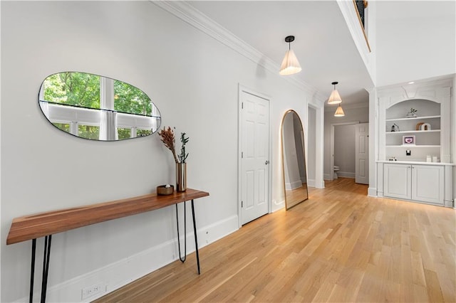 hall with built in features, crown molding, and light hardwood / wood-style flooring