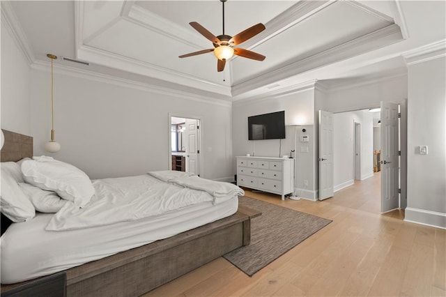 bedroom with ornamental molding, ensuite bath, ceiling fan, a raised ceiling, and hardwood / wood-style flooring