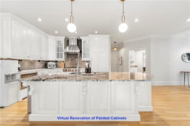 kitchen with a kitchen island with sink, wall chimney exhaust hood, light hardwood / wood-style floors, and hanging light fixtures