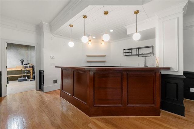 bar featuring crown molding, pendant lighting, sink, and light wood-type flooring