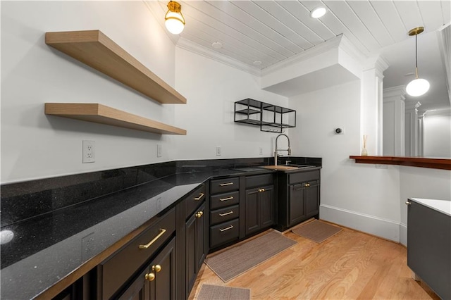 kitchen with crown molding, decorative light fixtures, light hardwood / wood-style floors, sink, and dark stone counters