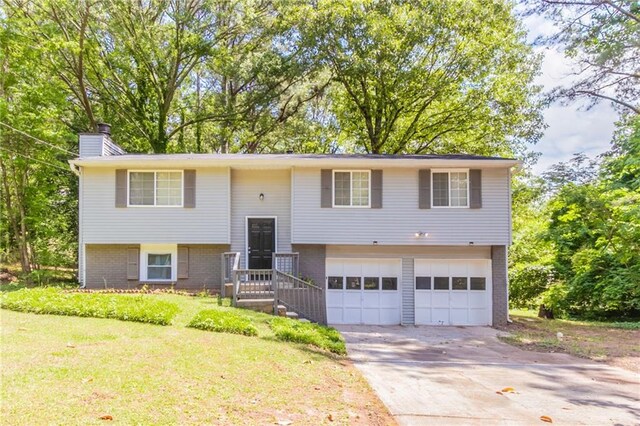 1051 S Millard Way, Stone Mountain, GA 30088 - bi-level home featuring an attached garage, brick siding, driveway, a chimney, and a front lawn