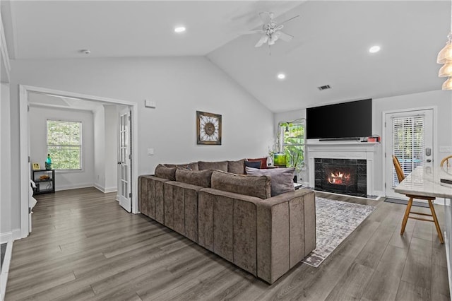 living room with lofted ceiling, a fireplace, ceiling fan, and light wood-type flooring