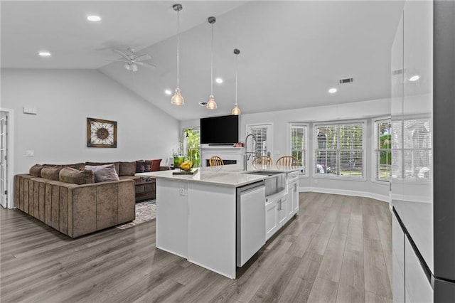 kitchen with dishwasher, a kitchen island with sink, white cabinets, decorative light fixtures, and light wood-type flooring