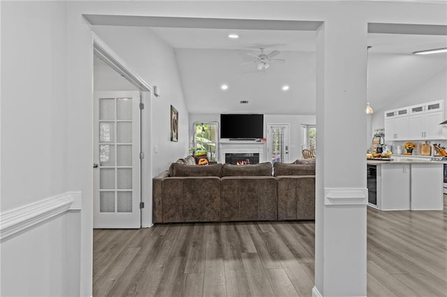 living room with ceiling fan, lofted ceiling, beverage cooler, and light hardwood / wood-style floors