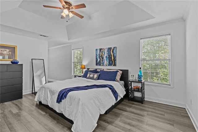 bedroom with hardwood / wood-style flooring, ornamental molding, and a tray ceiling