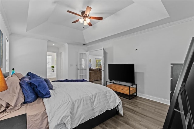 bedroom with a raised ceiling, wood-type flooring, ornamental molding, and ceiling fan