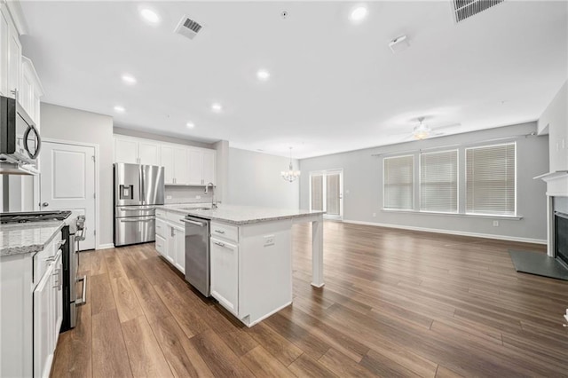 kitchen featuring a center island with sink, decorative light fixtures, sink, appliances with stainless steel finishes, and white cabinets