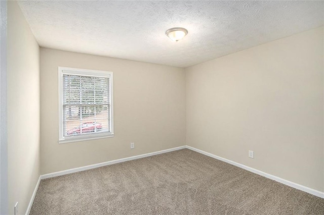 carpeted spare room featuring a textured ceiling and baseboards