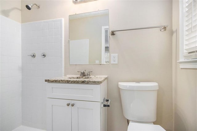 bathroom with tiled shower, vanity, and toilet