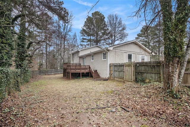 rear view of property featuring a deck, brick siding, a fenced backyard, and stairs