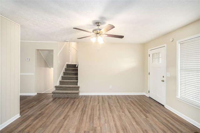 interior space featuring stairs, a textured ceiling, wood finished floors, and baseboards