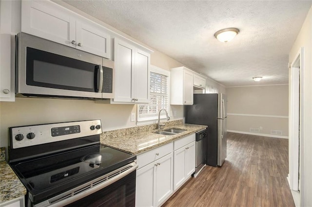 kitchen featuring white cabinetry, appliances with stainless steel finishes, a sink, and wood finished floors