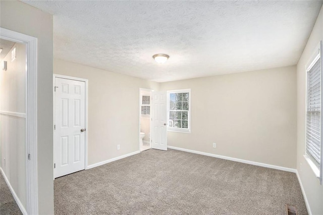 carpeted spare room featuring baseboards, visible vents, and a textured ceiling