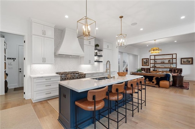 120 Nezhat Pl, Atlanta, GA 30350 - kitchen with custom range hood, a sink, a chandelier, light wood-type flooring, and tasteful backsplash