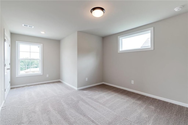 empty room with baseboards, visible vents, light carpet, and a healthy amount of sunlight