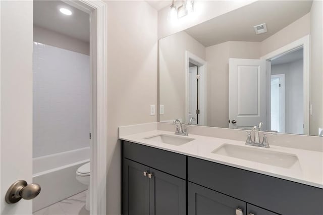 bathroom with double vanity, toilet, marble finish floor, and a sink