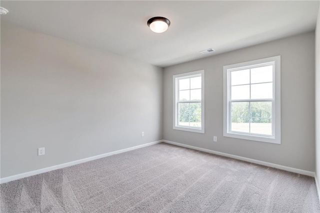 carpeted spare room with visible vents and baseboards