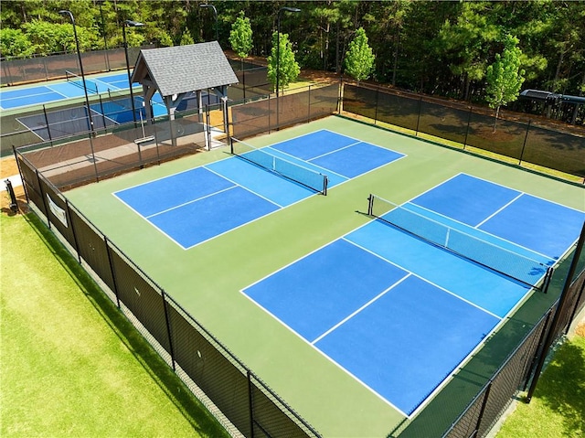 view of sport court featuring fence and a lawn