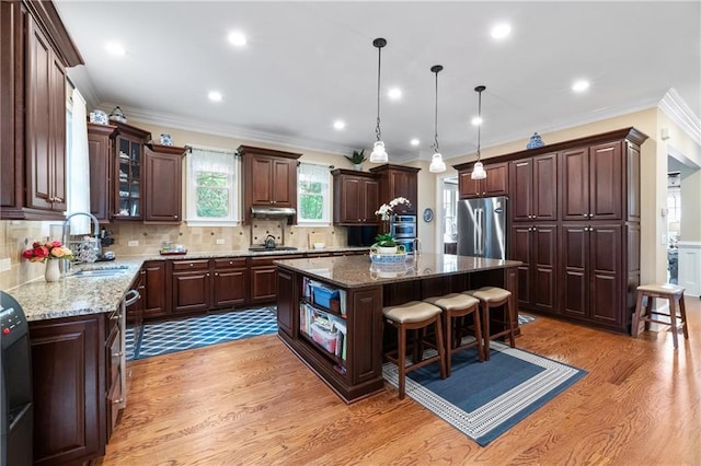 2283 Falmouth Ct SE Unit 22, Smyrna, GA 30080 - kitchen featuring appliances with stainless steel finishes, light wood-type flooring, a kitchen island, crown molding, and light stone counters